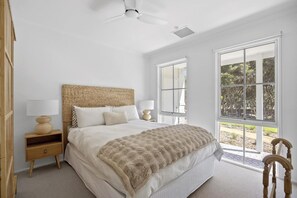 Un dormitorio con cama, mesita de noche, lámpara y ventana con vistas.