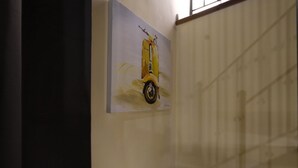 Una pared con un cuadro de un patinete amarillo.
