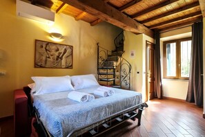 Un lit avec du linge de maison blanc et des serviettes pliées, un plafond en bois, un escalier et un tableau accroché au mur.