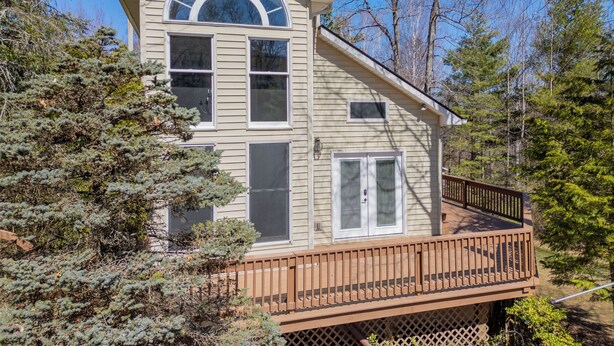 A two-story house with a balcony, surrounded by trees.