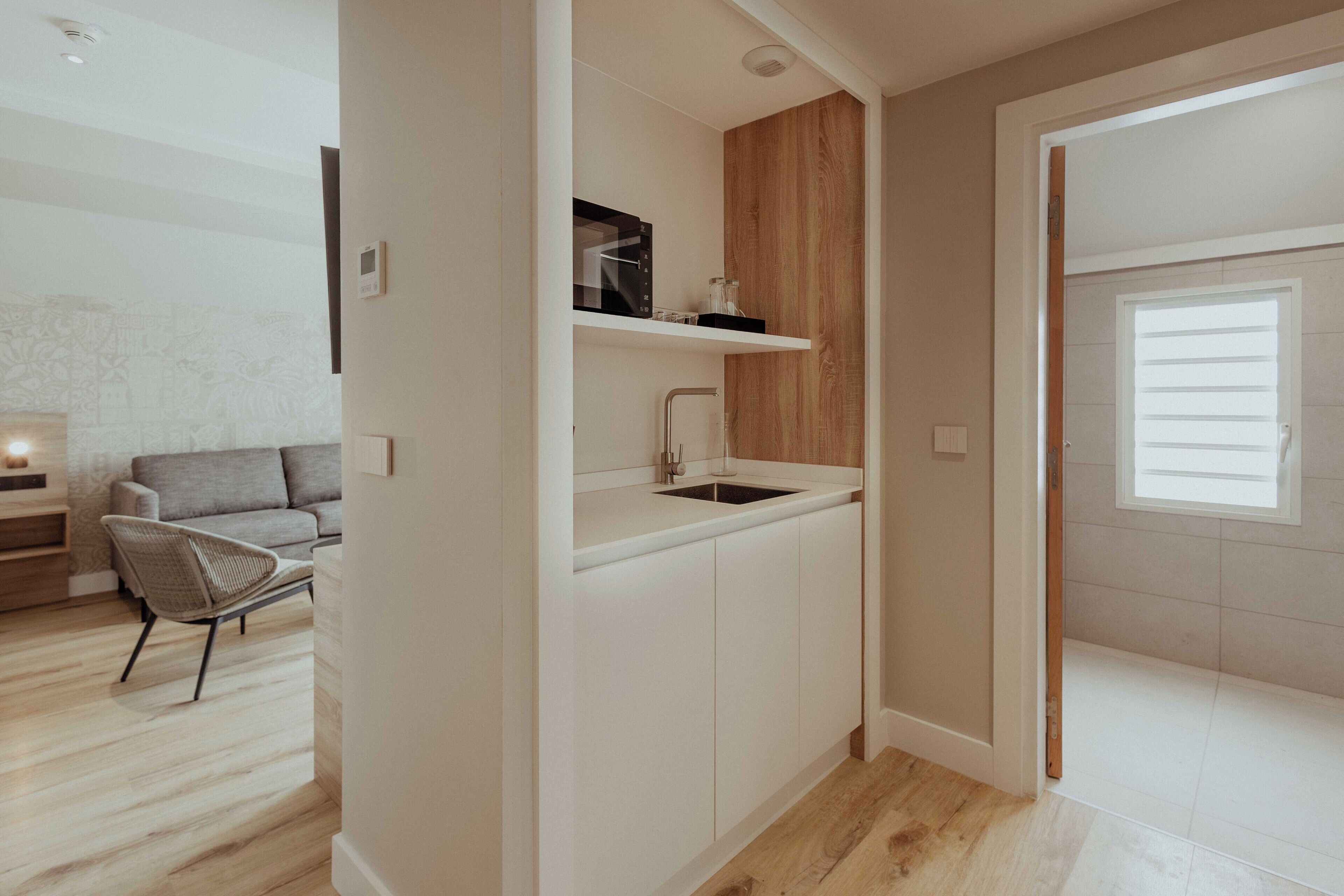 Una cocina moderna con armarios blancos, un panel decorativo de madera y un microondas integrado.