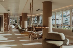 A spacious lobby with modern furniture, large windows, and a view of the cityscape. - Hotel Reva Tahiti (Papeete)