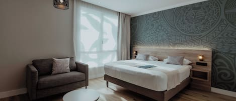 A modern bedroom with a bed, a sofa, a round table, and a patterned wall.