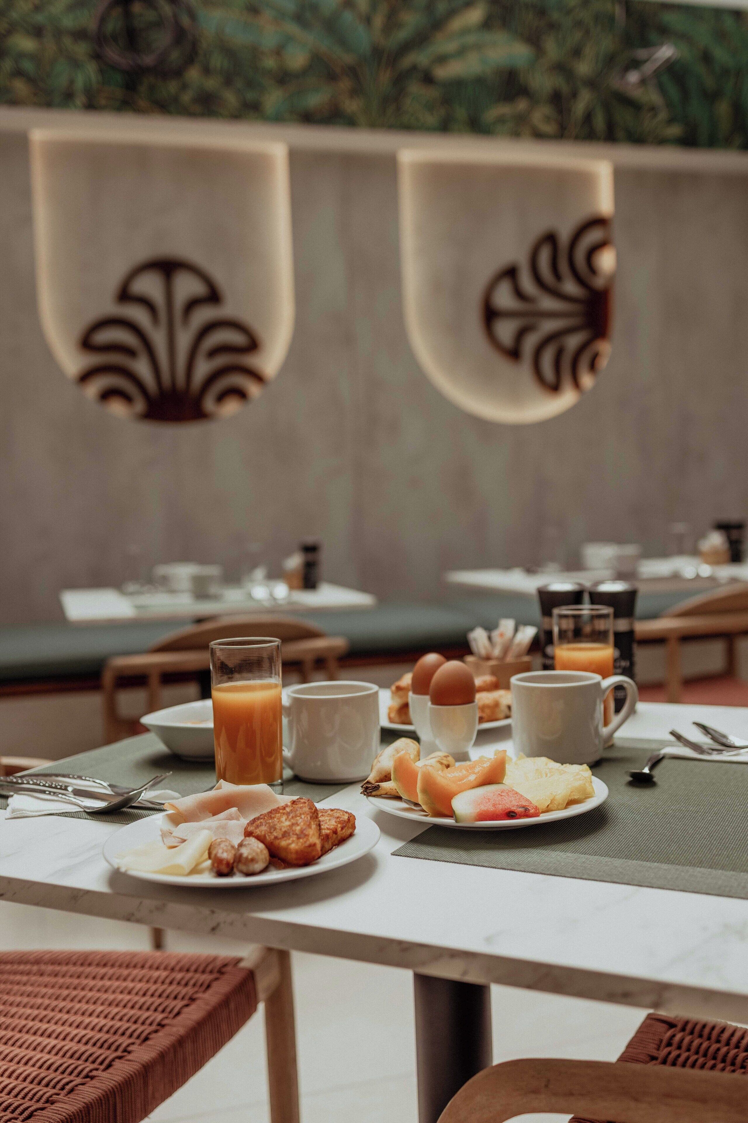 A breakfast table with plates of food, glasses of orange juice, and a coffee pot.