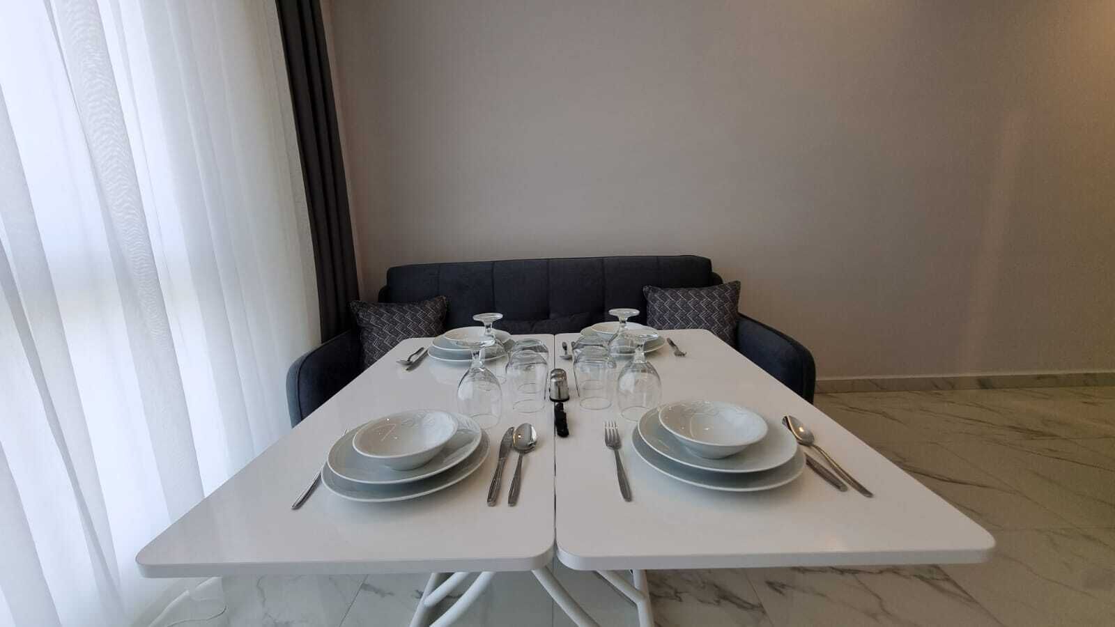 A dining table set for two with plates, cutlery, and wine glasses.
