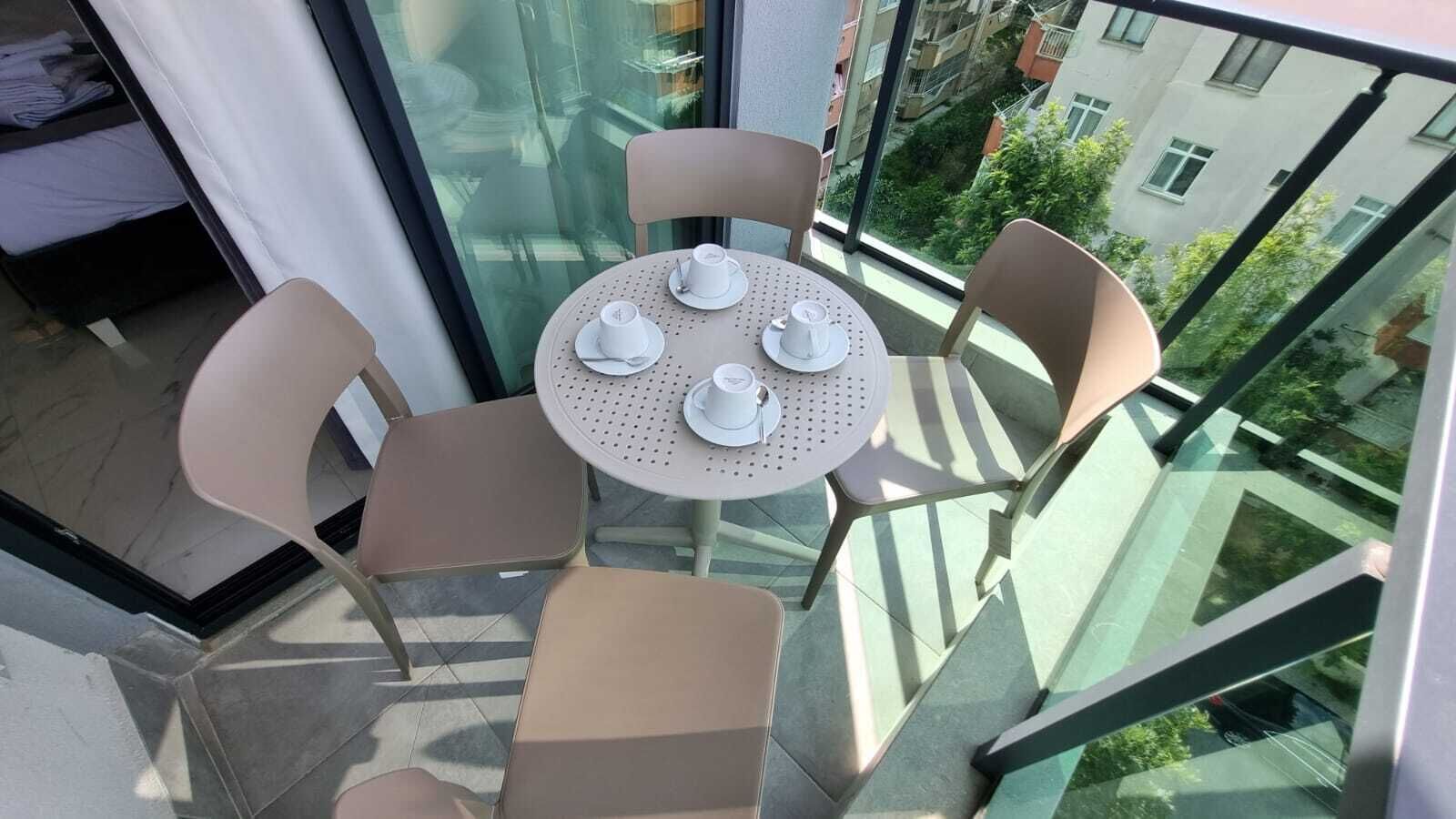 A balcony with a round table and four chairs, each with a cup and saucer.