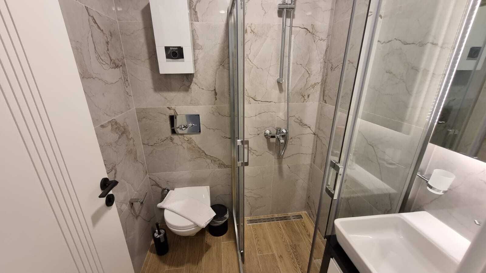 Un baño moderno con ducha de vidrio, inodoro y lavamanos.