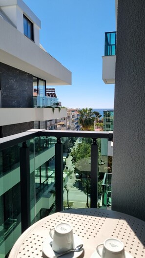 Ein Balkon mit Tisch, Stühlen und Blick auf die Stadtlandschaft und Palmen.