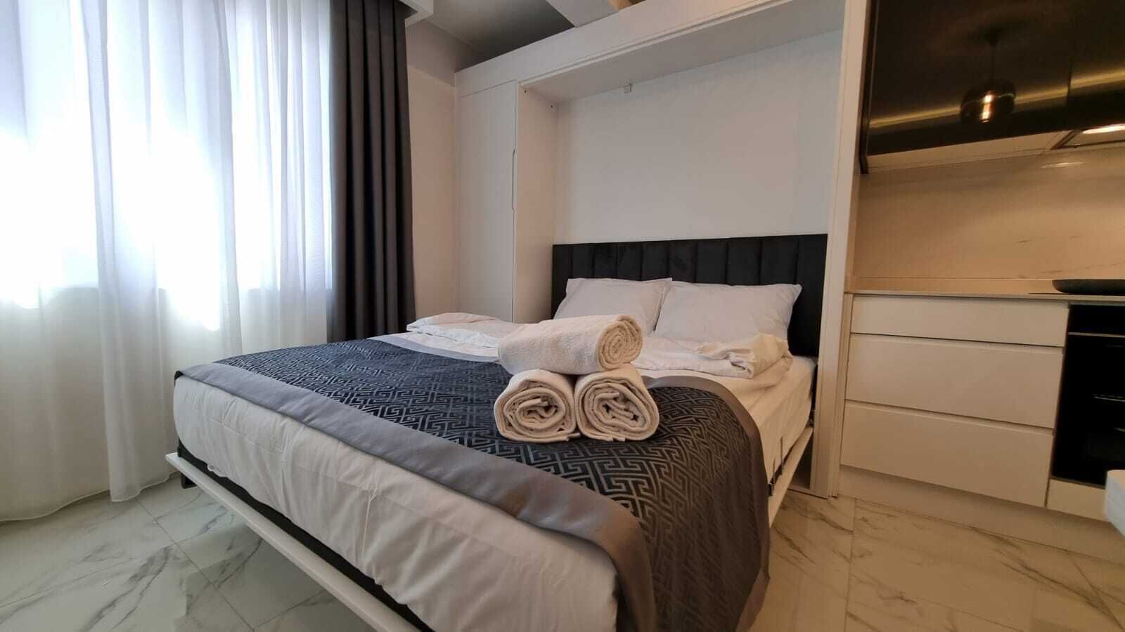 A modern hotel room with a neatly made bed, a built-in wardrobe, and a marble floor.