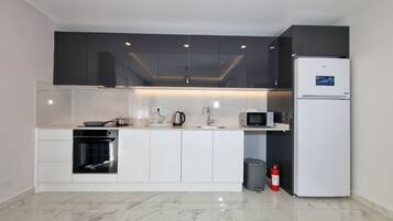 A modern kitchen with white cabinets, a built-in oven, a microwave, and a refrigerator.