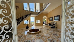 A spacious foyer with a grand staircase, a seating area with a sofa and armchairs, and a decorative tiled floor. - Villa Saran, amazing seafront in Sorrento center (Sorrento)