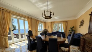 A dining room with a large table, chairs, and a chandelier. There are curtains, a sofa, and a cabinet. - Villa Saran, amazing seafront in Sorrento center (Sorrento)