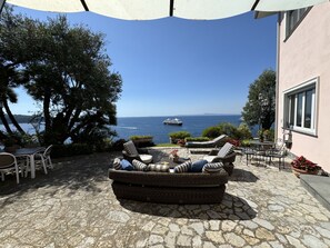 A patio with wicker furniture, a stone floor, and a view of the sea.