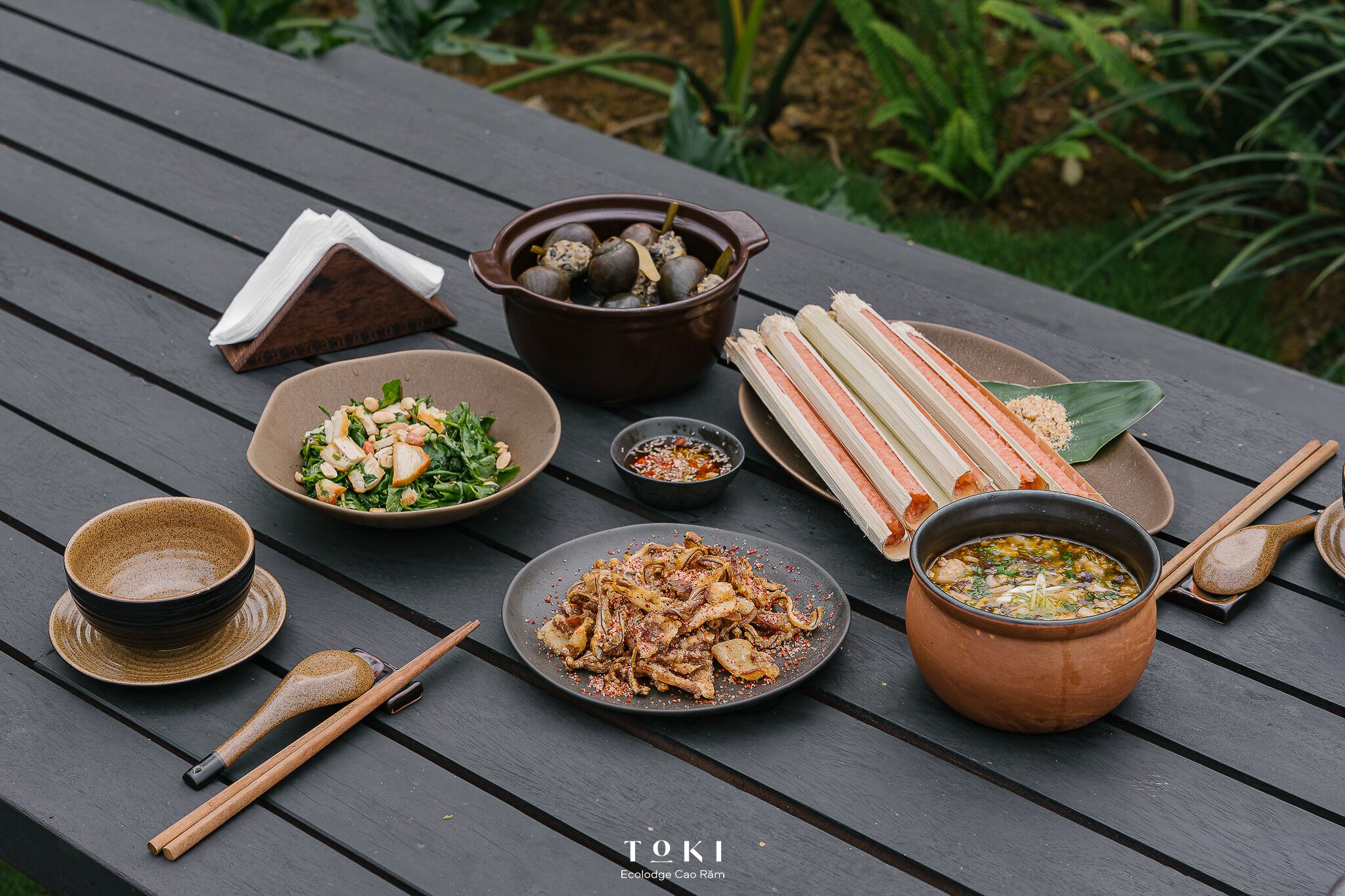 A table with various dishes, including a bowl of soup, a plate of noodles, and a bowl of salad.