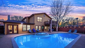 Ein Haus mit Swimmingpool, überdachter Terrasse und einem Hinterhofdeck mit Liegestühlen.