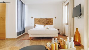 A hotel room with a wooden headboard, a bed with white linens, a flat-screen TV on the wall, and a breakfast tray on the side table. - Oro Biancu (Lucciana)