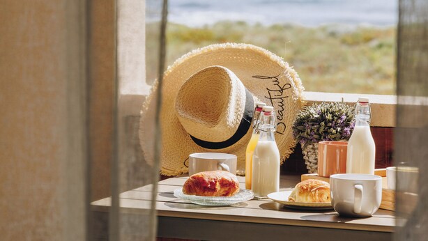 A table with breakfast items, a straw hat, and a view of the ocean. - Oro Biancu (Lucciana)
