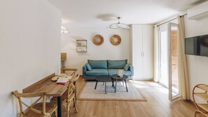 A modern living room with a wooden dining table, chairs, a sofa, and a TV. - Oro Biancu (Lucciana)