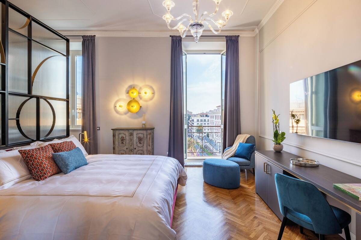 A modern bedroom with a large bed, a desk, and a view of the city.