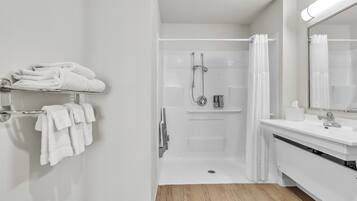 Une salle de bain moderne avec une douche à l’italienne, un lavabo blanc et un porte-serviettes.