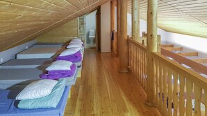 Una camera del dormitorio con letti a castello, ringhiere di legno e pavimento in legno.