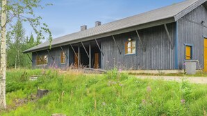 Un rustico chalet in legno con veranda, camino e un piccolo giardino.