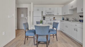 A modern kitchen with white cabinets, a microwave, and a dining area with a round table and four chairs.