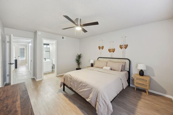 A bedroom with a bed, bedside tables, a ceiling fan, and a potted plant. - The Landry 174 | Spacious and Cozy 2 Bedroom 2 bth (Arlington)