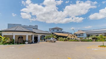 Ein Hotel mit einer Rezeption, einem Parkplatz und einem davor stehenden Auto.