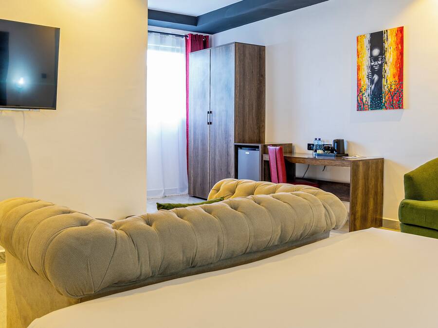 Une chambre d’hôtel moderne dotée d’un grand lit, d’un téléviseur à écran plat, d’un bureau avec une chaise et d’une œuvre d’art colorée accrochée au mur.