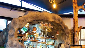 Un rústico espacio de bar con mobiliario de madera y un arco de piedra.