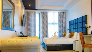 Habitación de hotel con una cama grande, un sofá, un escritorio y un televisor montado en la pared.