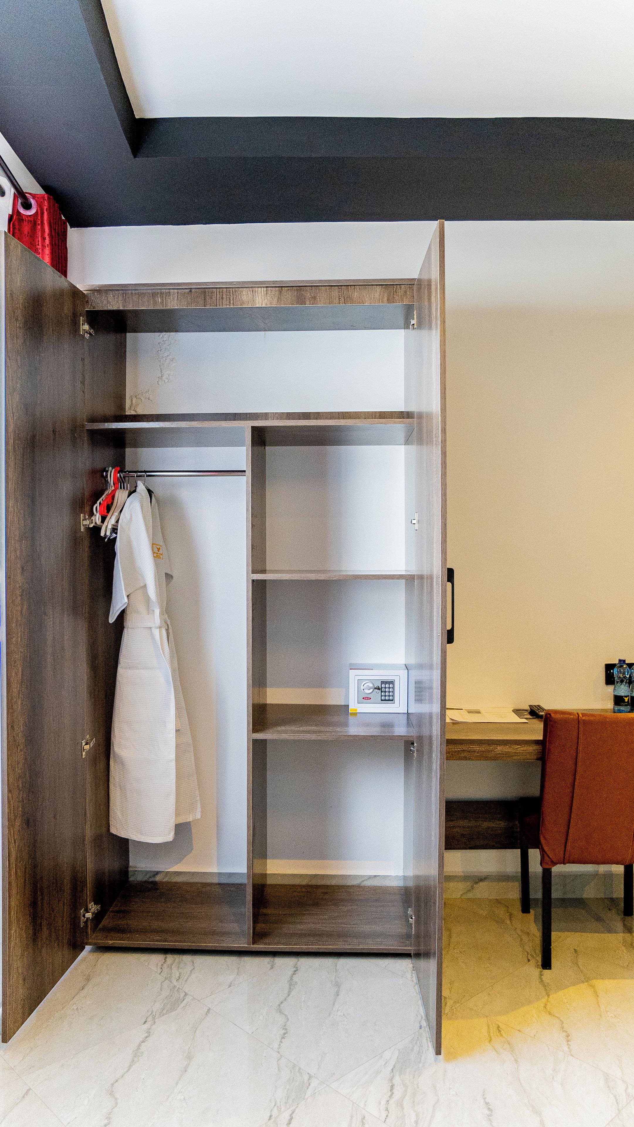A walk-in closet with a hanging rack, a small safe, and a desk with a chair.