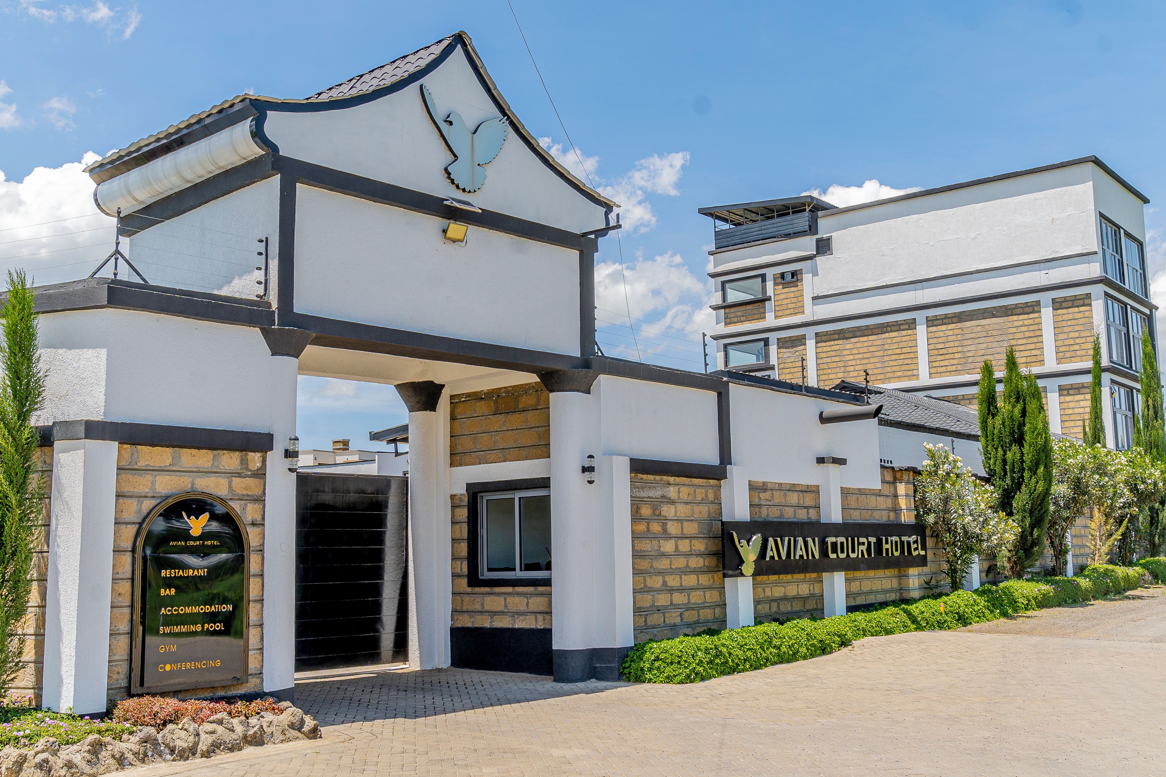 A hotel entrance with a sign indicating amenities like a restaurant, bar, accommodation, swimming pool, gym, and conferencing facilities.