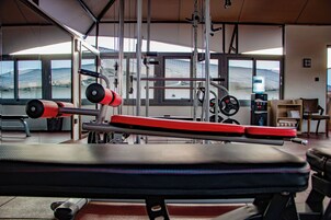A gym with exercise equipment, large windows, and a water dispenser.