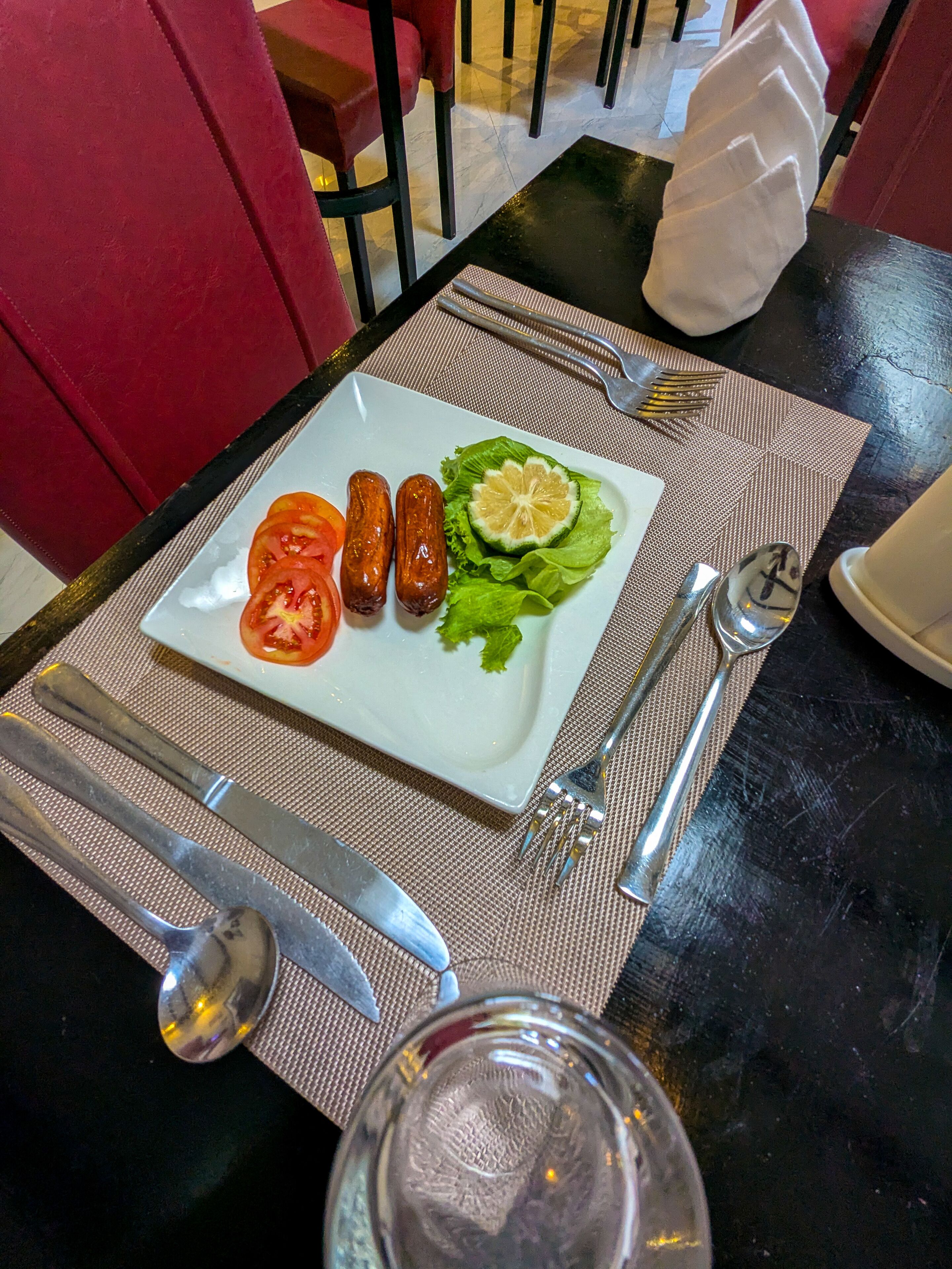A dining table with a plate of food, utensils, and a napkin.