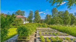 Un jardín con camas elevadas y una terraza de madera.