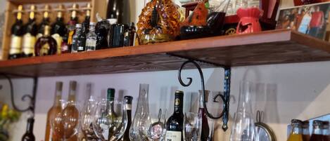 Zona de bar con estantes llenos de botellas y copas.