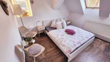 Une chambre à coucher avec un lit, une chaise, une table de chevet, une lampe et une fenêtre.