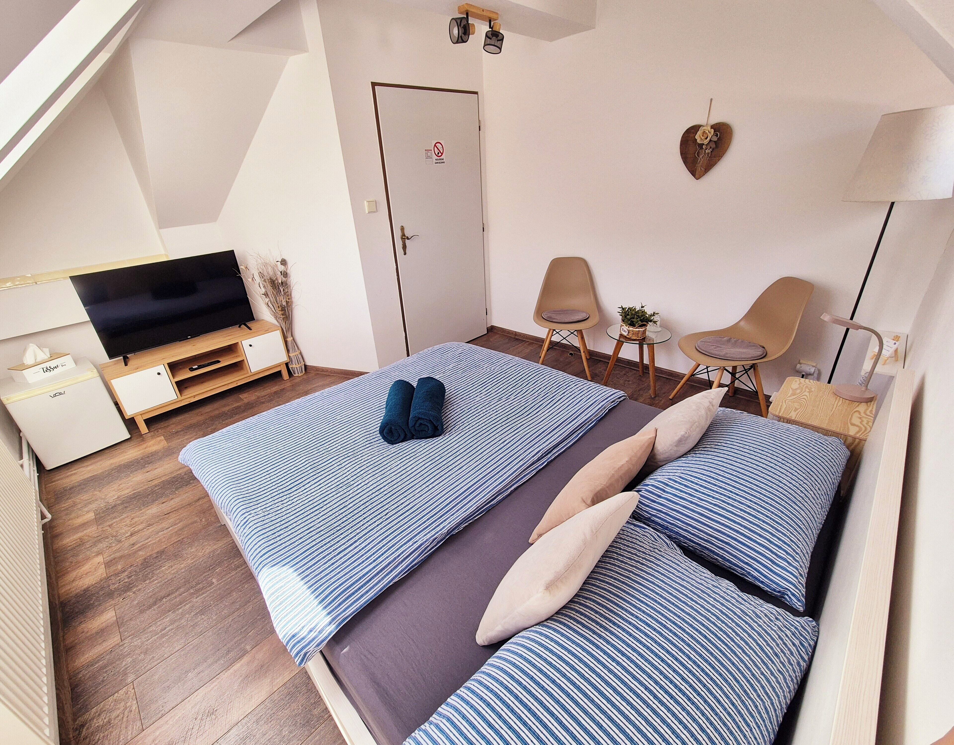 Een slaapkamer met een bed, een televisie, een bureau en een stoel.