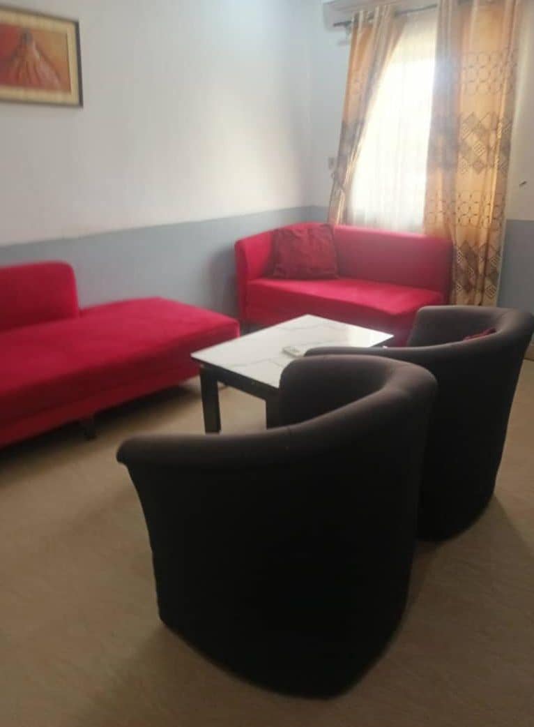 A room with two red sofas, a white table, and two black armchairs.