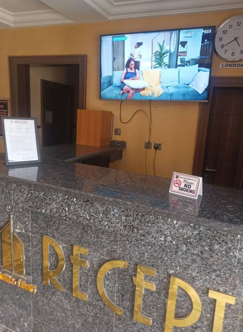 A reception desk with a television mounted above it displaying a scene.