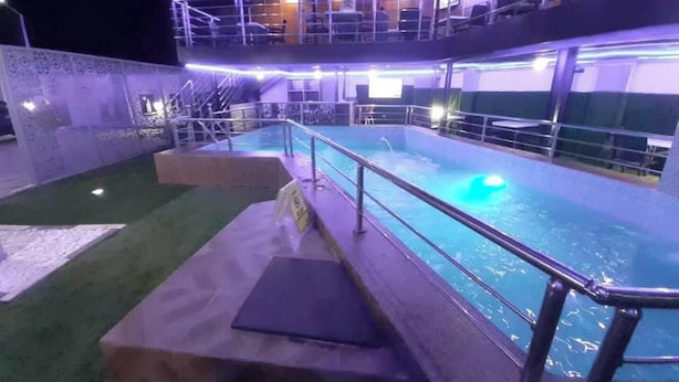 An indoor swimming pool with a glass barrier and steps leading to a viewing area. - Angels Court Hotel and Suite (Abuja)