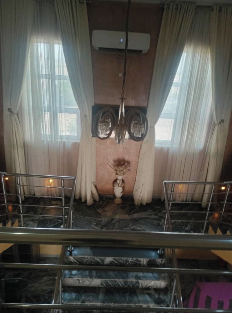 Een kamer met een marmeren vloer, een kroonluchter en een groot raam met gordijnen.