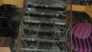 A marble staircase with metal railings, a vase with dried flowers, and a striped cushion on the floor. - Angels Court Hotel and Suite (Abuja)
