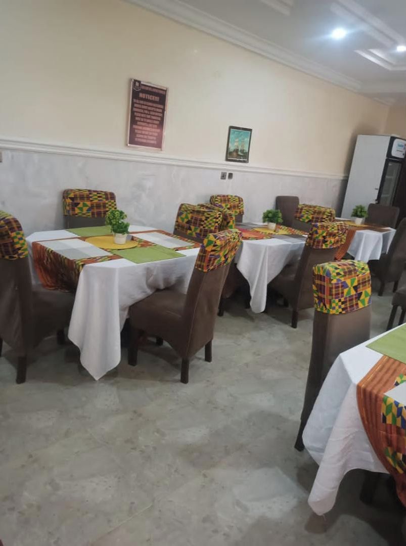 Un comedor con mesas cubiertas por manteles blancos y sillas con cojines estampados.