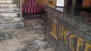 A hotel reception area with a marble staircase, a reception desk, and a striped chair. - Angels Court Hotel and Suite (Abuja)