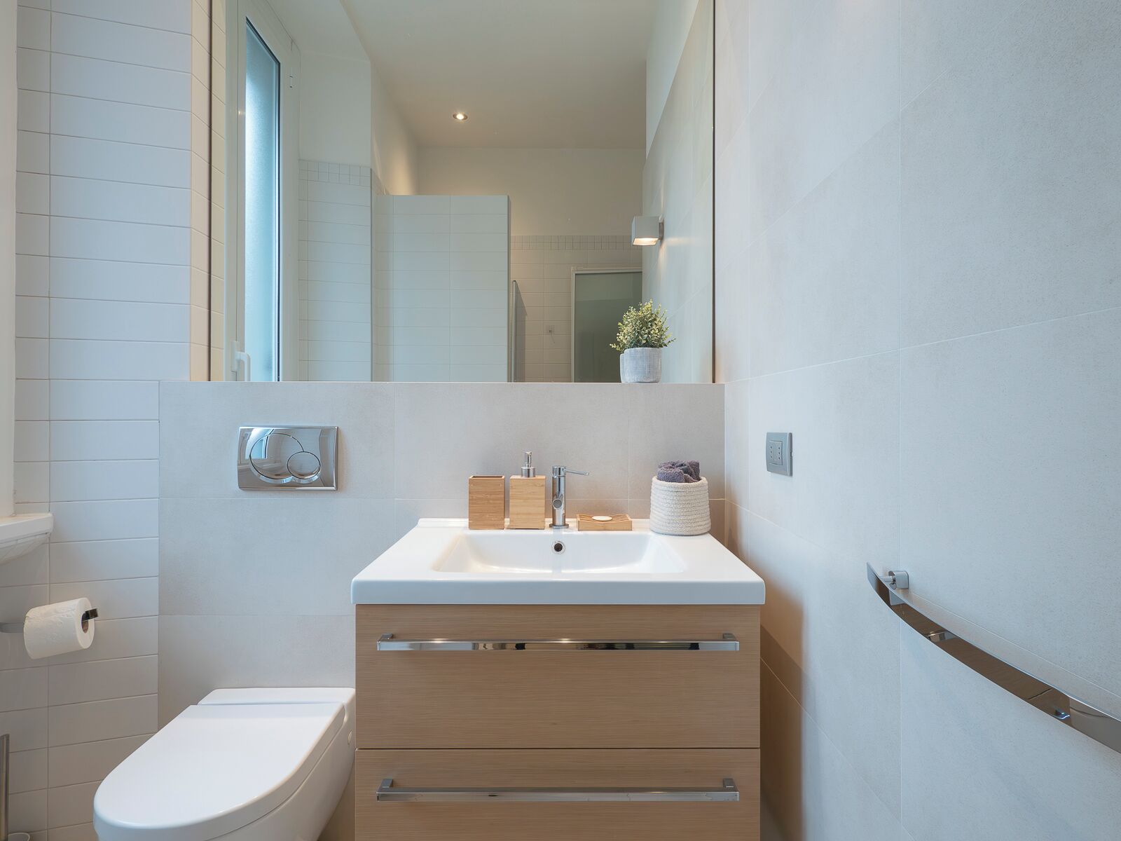 Et moderne badeværelse med en hvid vask, en trækommode og et toilet.