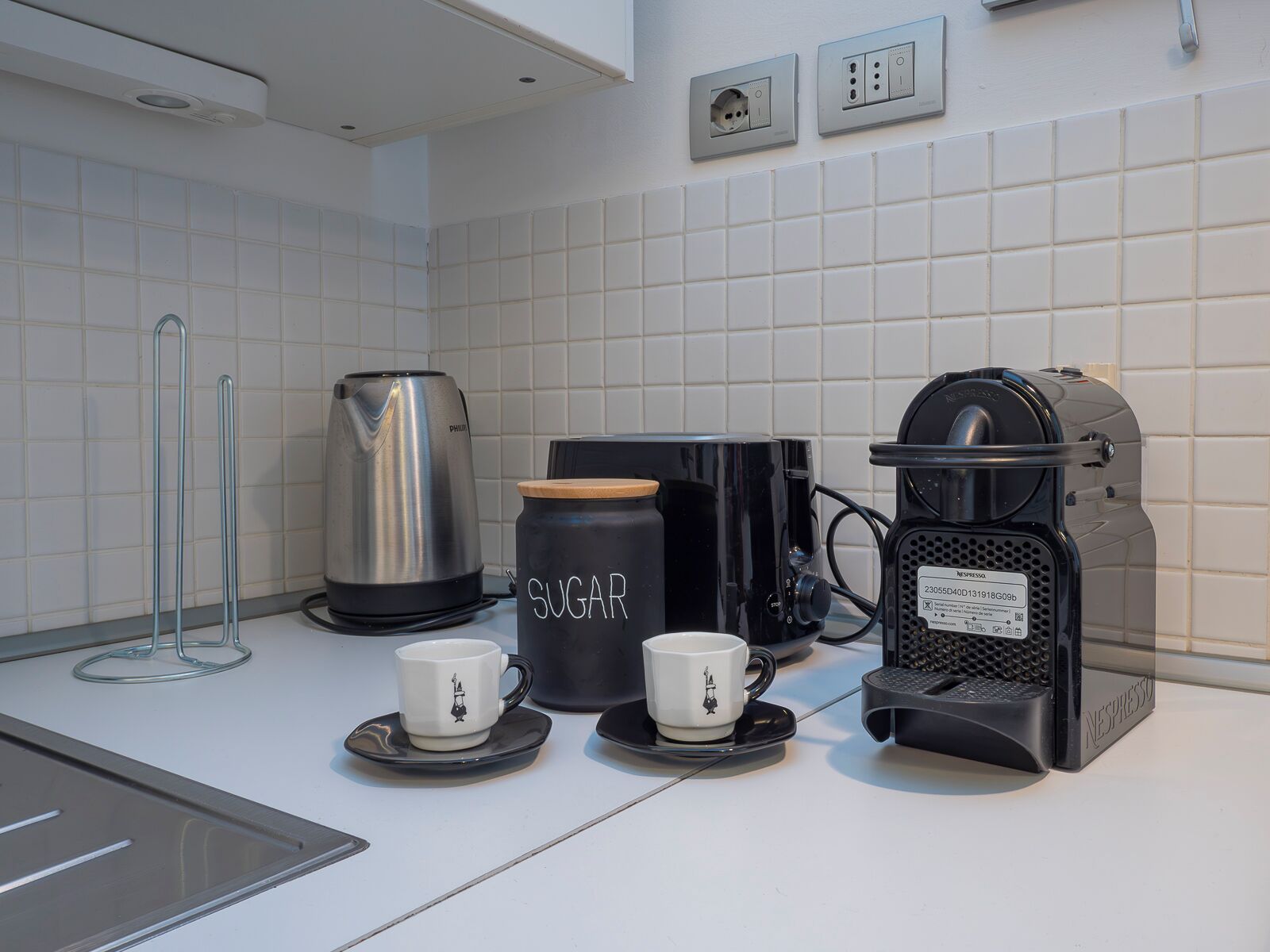 Ett modernt kök med en kaffebryggare, en vattenkokare och två koppar på bänkskivan.