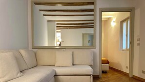 Una sala de estar moderna con un sofá blanco, vigas de madera en el techo y un espejo grande.